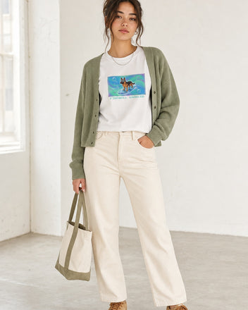 O's Tees Firewall Enabled German Shepherd Frutiger Aero Dogs graphic tee lifestyle image — White shirt, female shot 02, sage cardigan cream denim