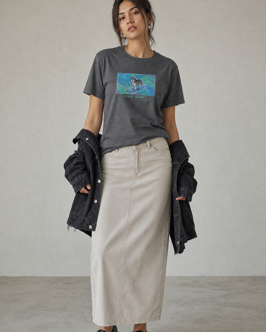 O's Tees Cold Start Husky Frutiger Aero Dogs graphic tee lifestyle image — Graphite Heather shirt, female shot 02, stone column skirt black jacket